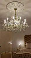 Хрустальная люстра Мария Терезия в золотом исполнении в роскошной спальне с мягкой мебелью